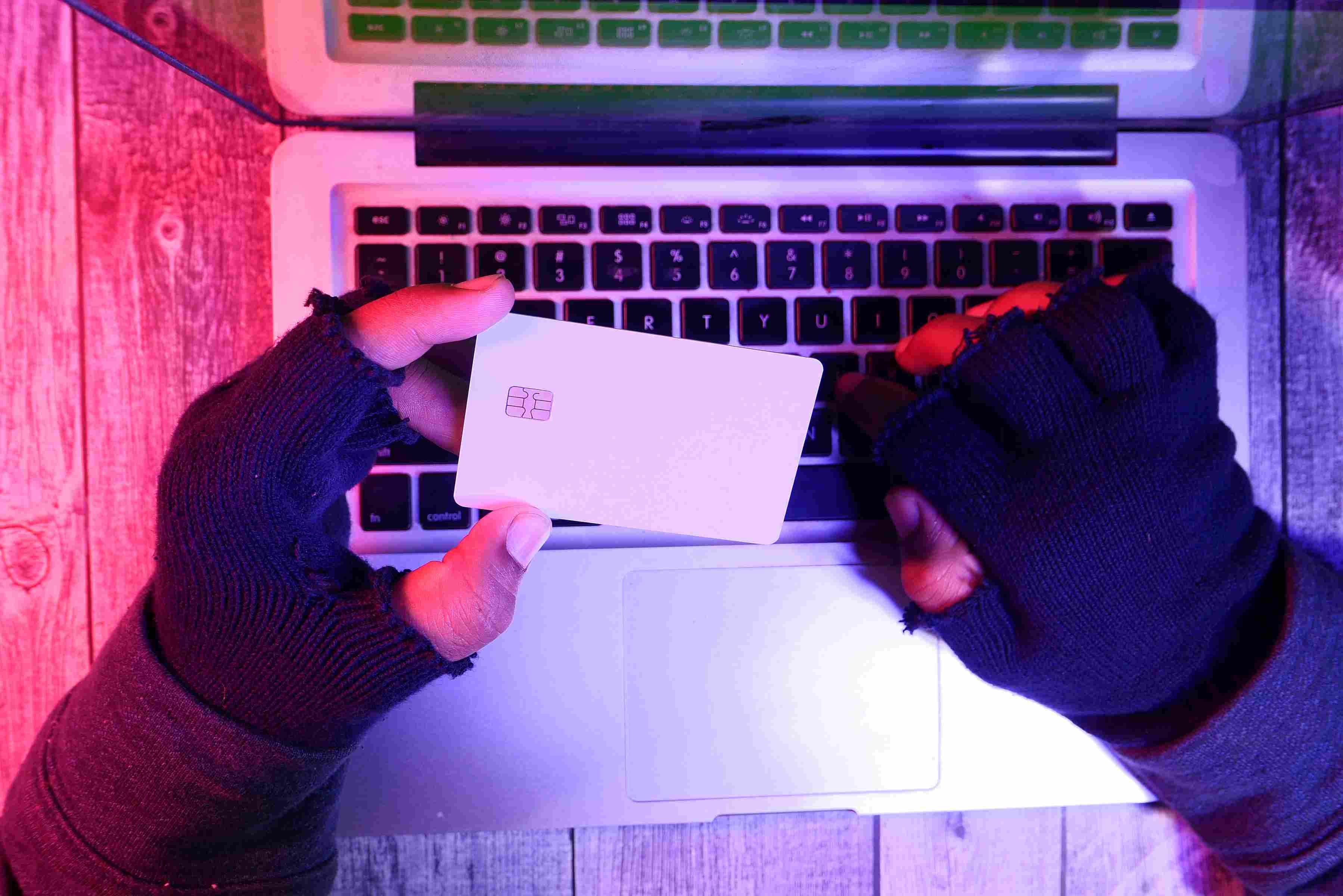 Gloved hands holding a credit card over a laptop